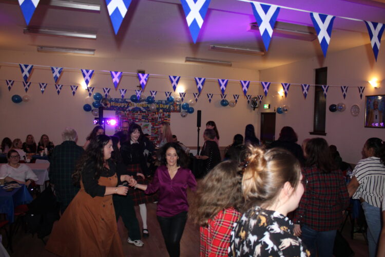 St. Andrews night 26 A group of people dancing together in a hall.
